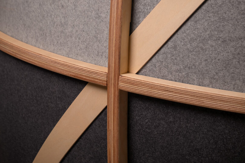 Close-up detail of intersecting light wood slats and textured felt panels.