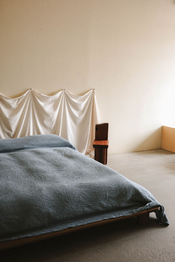 The Emmanuella Coverlet in Celeste hung as a headboard using oversized silvery hooks.