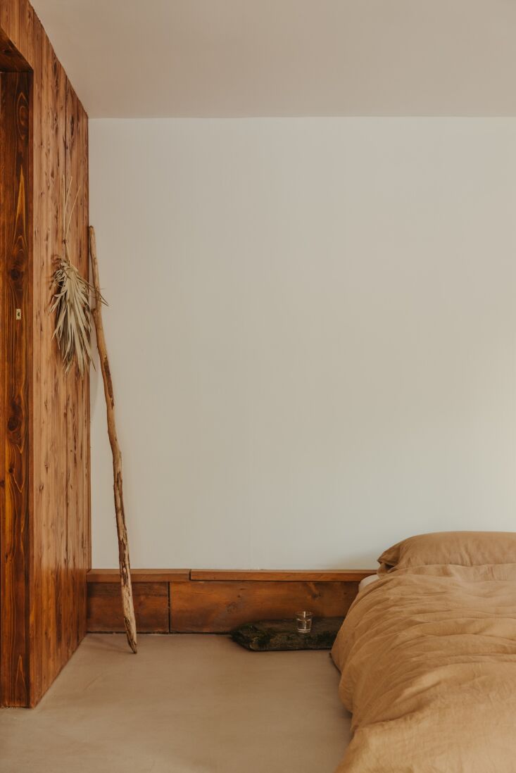 A low-profile fir bed frame in a wood-paneled bedroom.