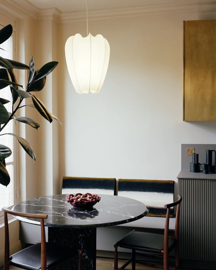 A black marble dining table and built-in bench in a compact Parisian dining nook.