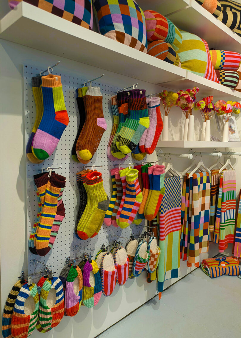 Display of colorful knitted striped and checkered textiles in a retail environment.
