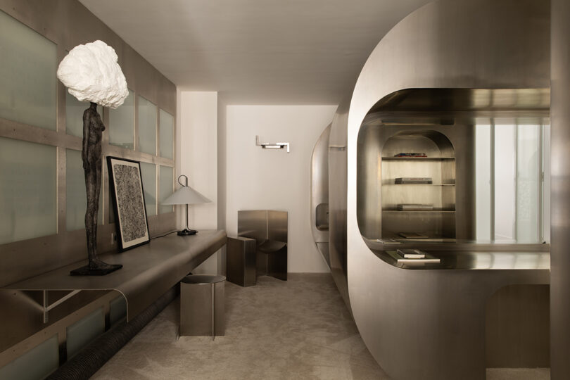 A minimalist room with metallic furniture and an abstract sculpture lamp.