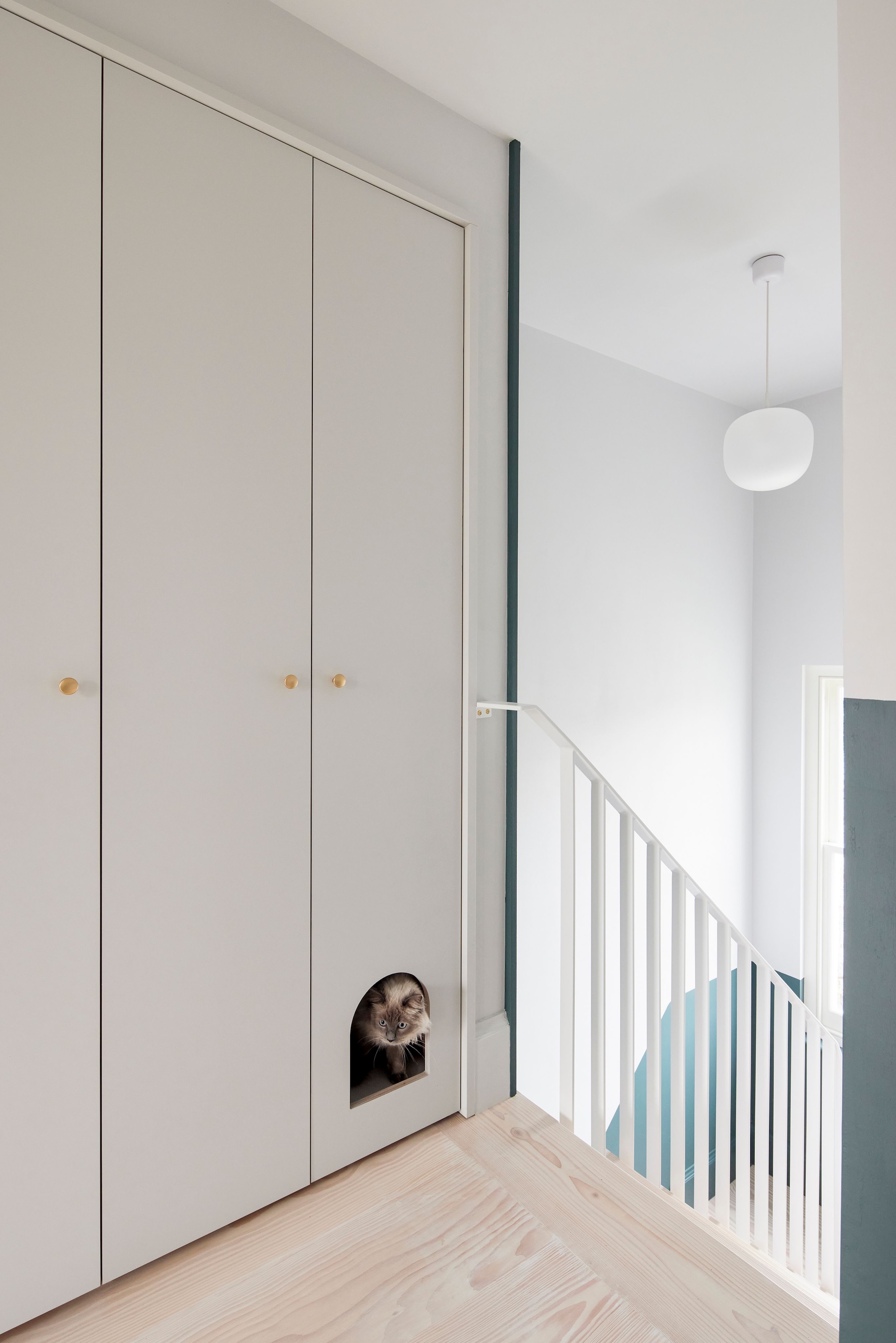 Custom light wood cabinetry with a circular cutout serving as a discreet entry for a cat litter box.