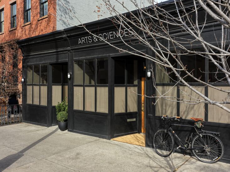 A historic storefront with three doors and large windows in a Brooklyn neighborhood.