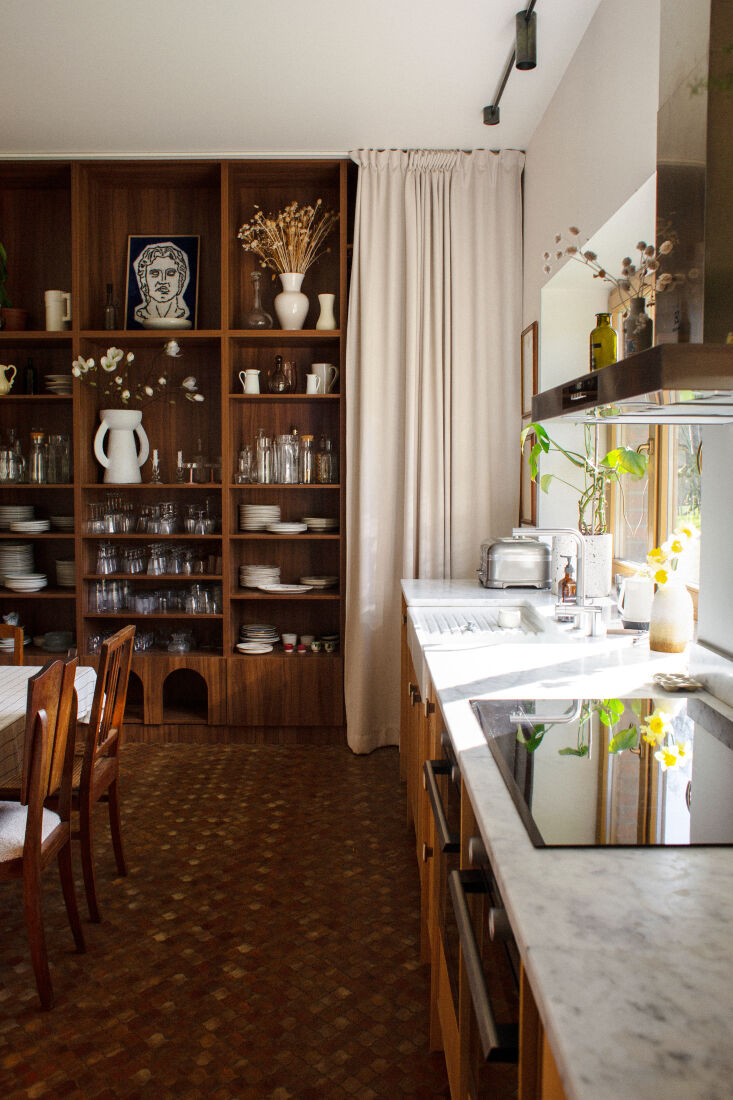 A high-design kitchen with tiled walls and floor-to-ceiling curtains.