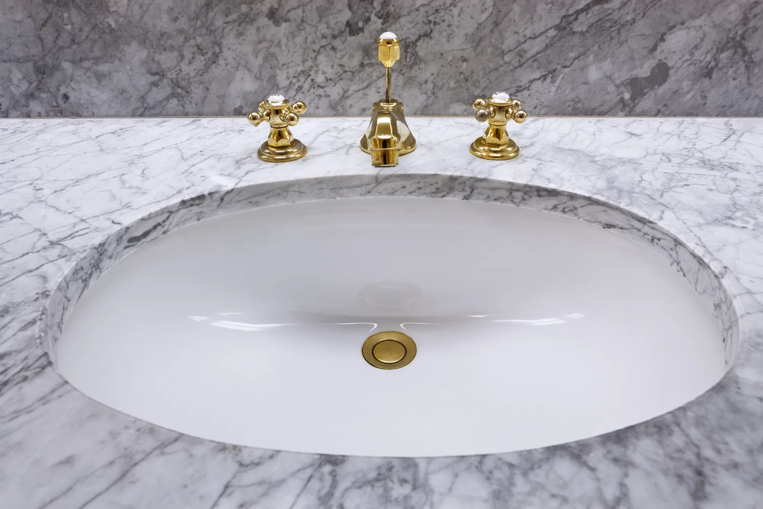 A luxury bathroom vanity with marble countertop and vintage-style brass fixtures including a traditional drain assembly.