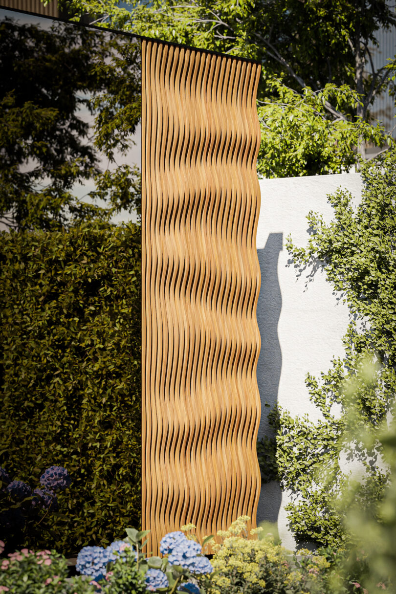 A tall wooden panel with a wavy, sculptural texture standing in a garden setting.