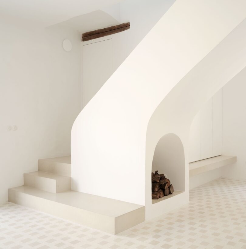 A minimalist white staircase with beige steps and an alcove for firewood.