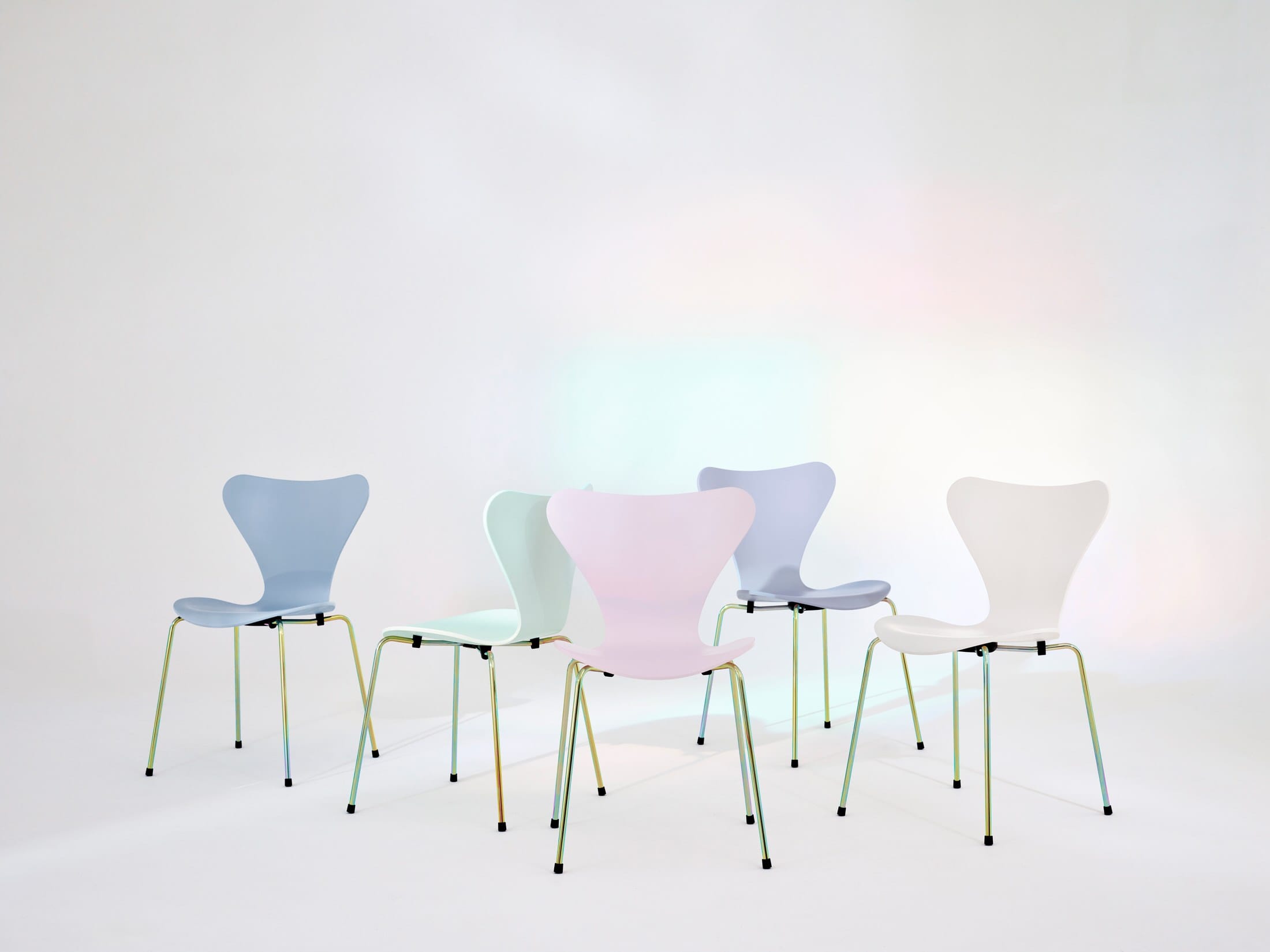 A stack of Series 7 chairs in various iridescent pastel colors like pink, blue, and green.