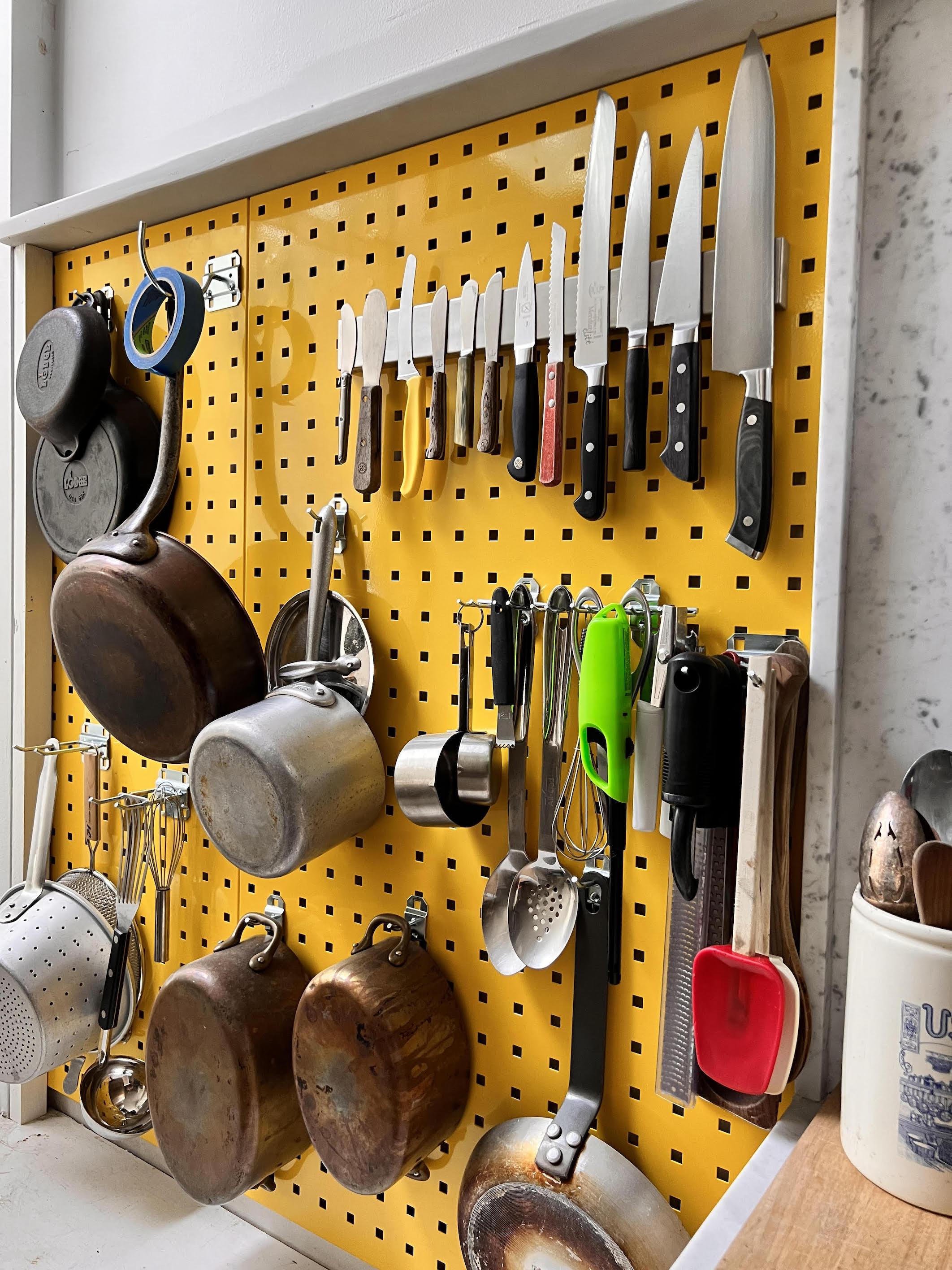 Technical detail of two metal pegboard panels being joined together and anchored into a wall.