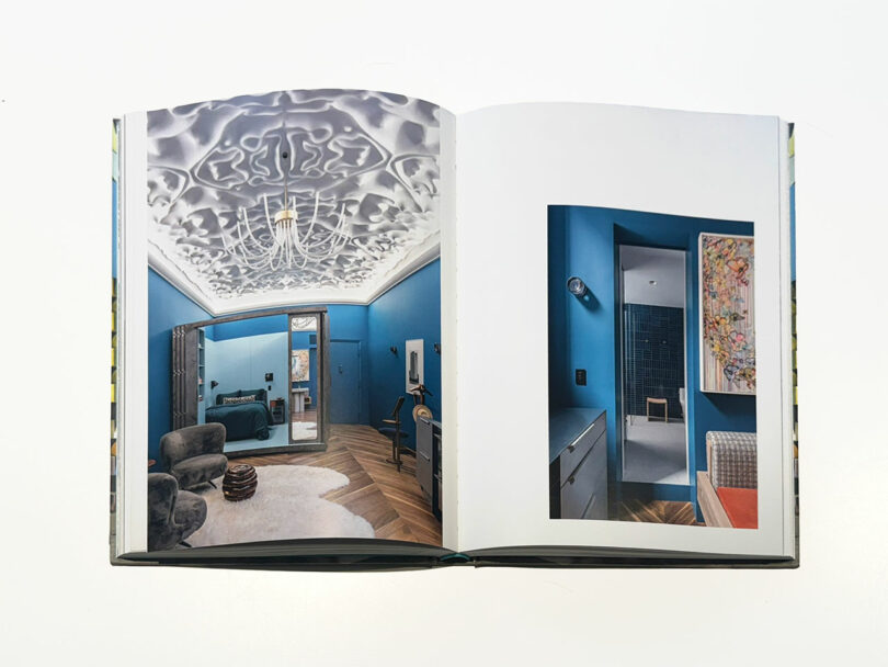 An open interior design book displaying a vibrant blue room with sculpted architectural details.