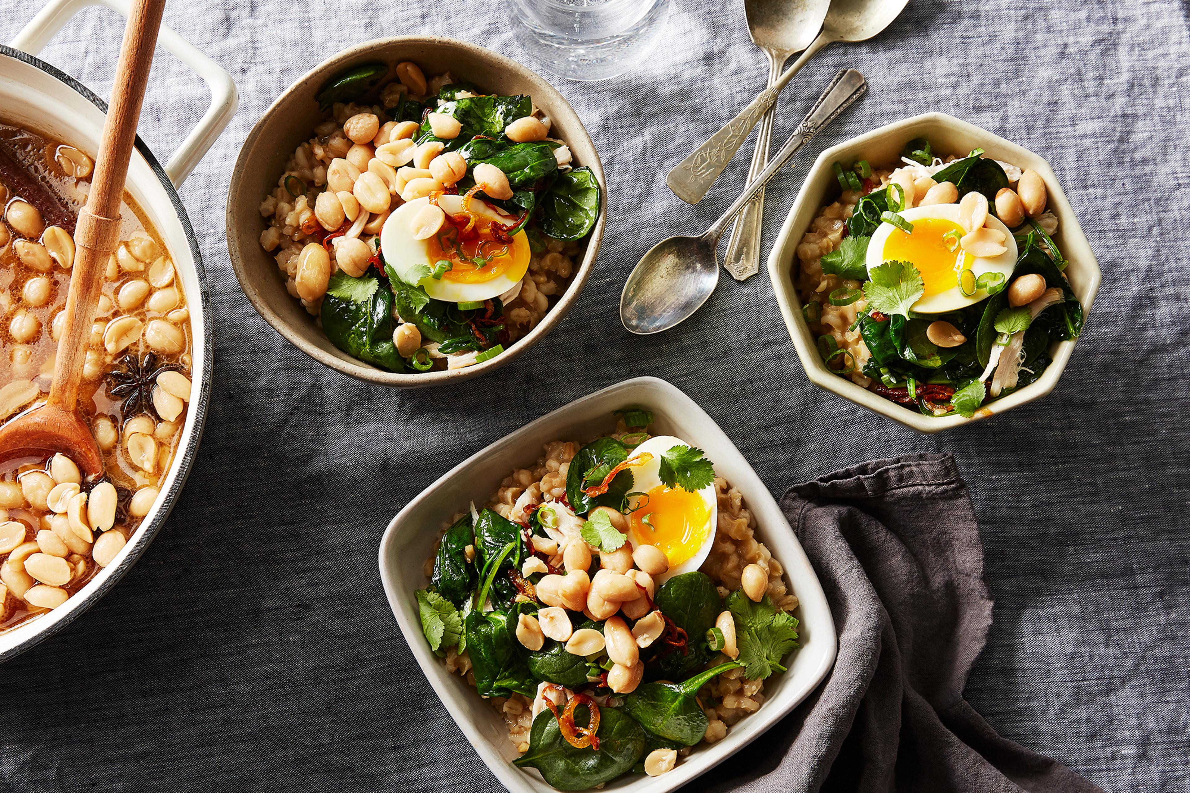 Multiple small bowls containing different congee toppings like spring onions, eggs, and crispy oils.