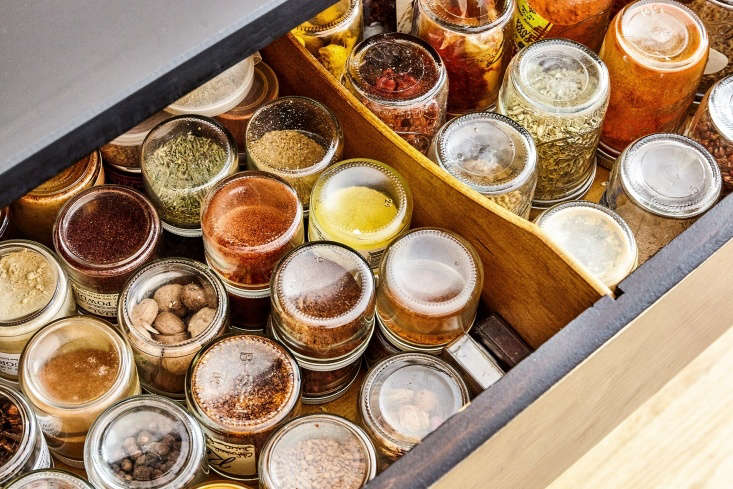 Glass spice jars stored upside down in a drawer showing the labels on the bottom of the jars.