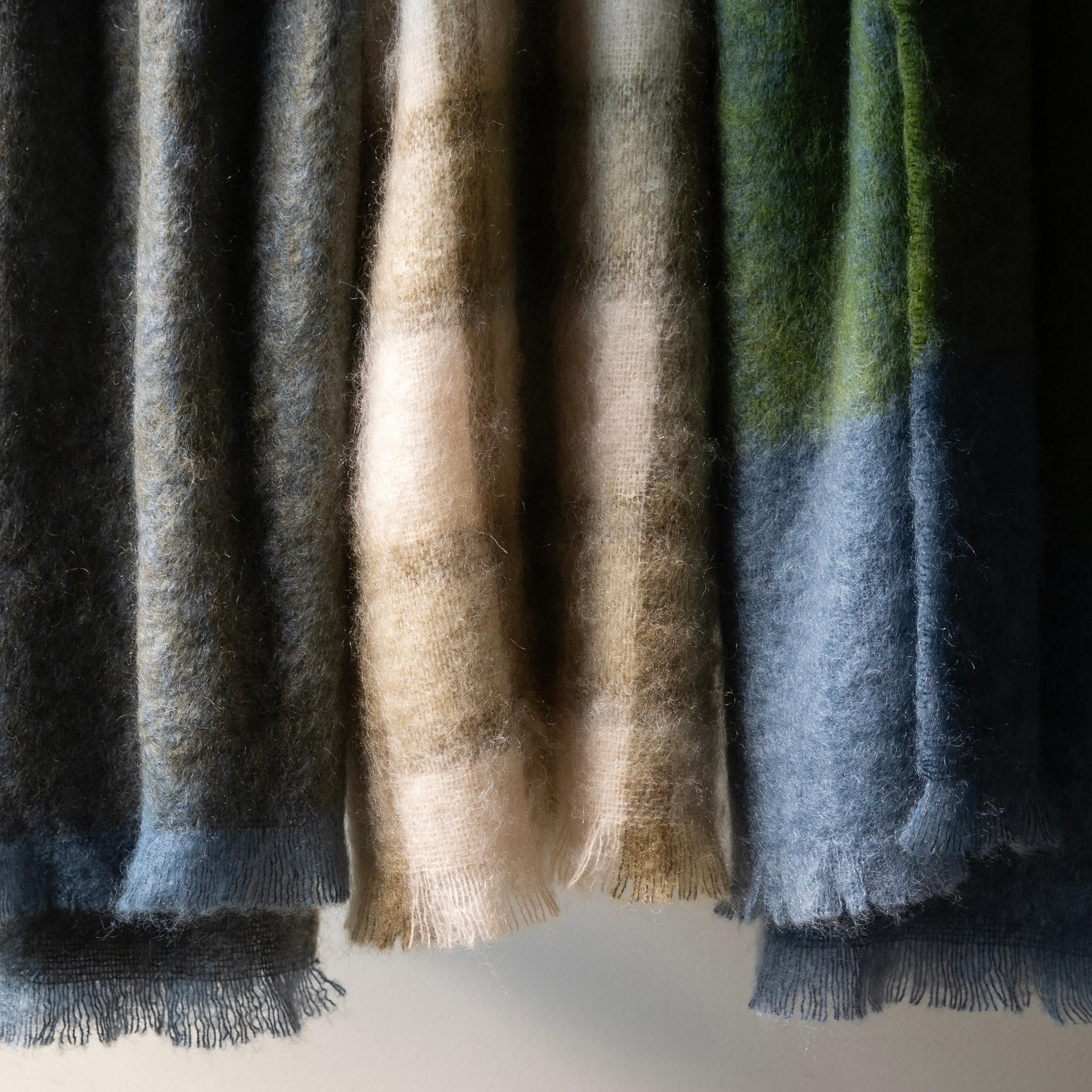 Close-up of soft mohair throw scarves in various muted tones.