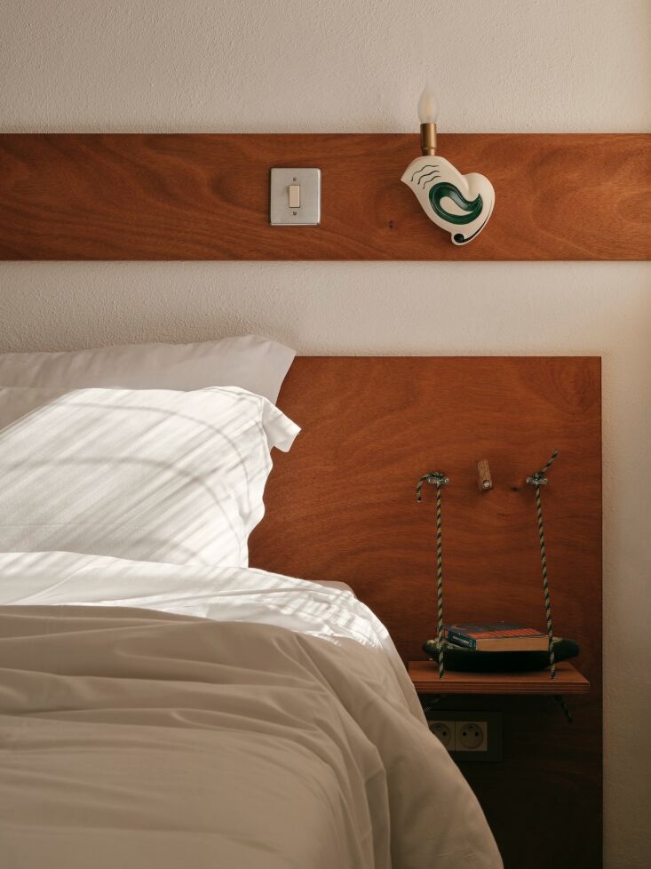 Close-up of a wooden nightstand suspended by thin ropes with a wooden latch at the top.