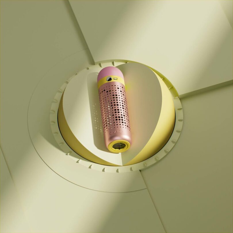 A pink and yellow perforated device positioned upright against a circular, pale yellow geometric background.