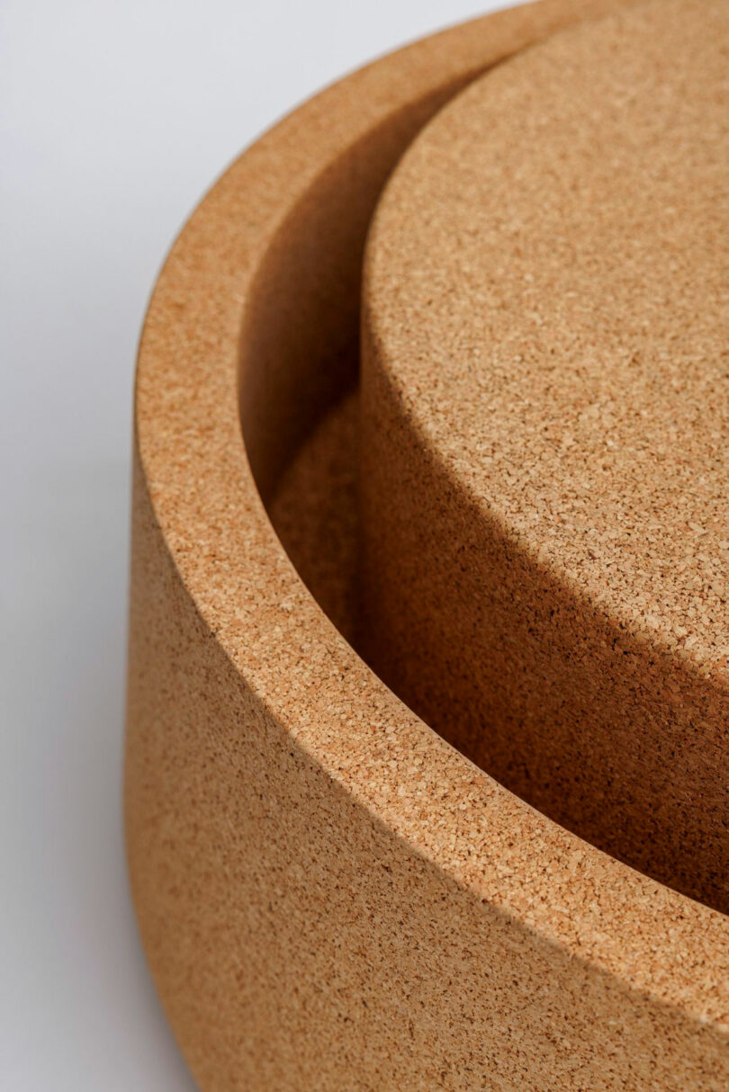 A detailed close-up of two cylindrical cork objects nested together, showcasing the grainy texture of recycled cork.