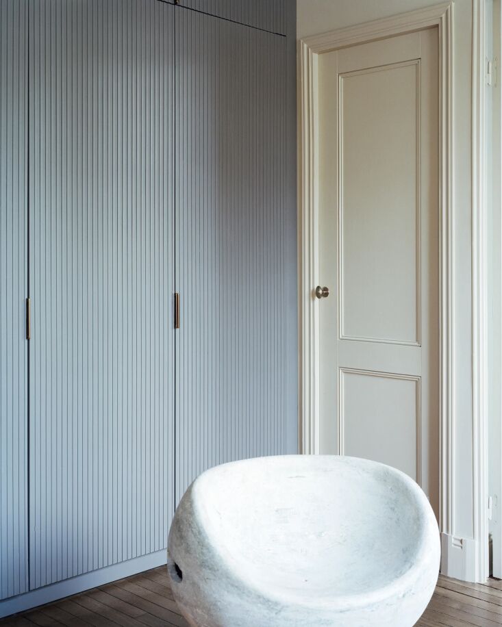 Built-in grey-blue cabinetry lining the perimeter of a small apartment entryway and kitchen.