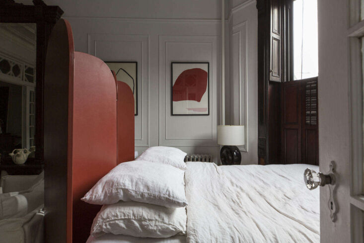 A red-painted custom folding screen used to divide a bed from a living area in a Brooklyn apartment.