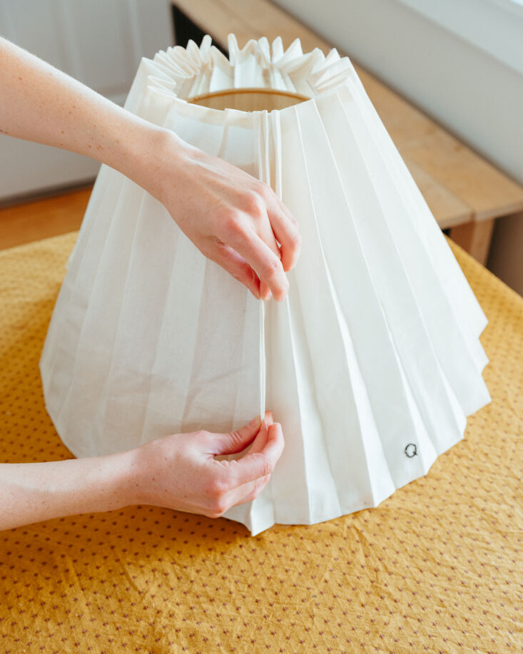 Gluing the two ends of the pleated fabric together to complete the shade.