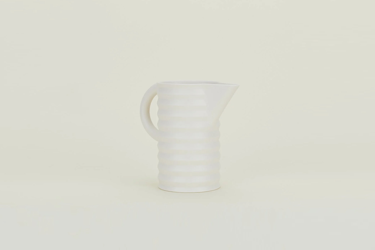 A white pitcher with a unique pleated surface texture.