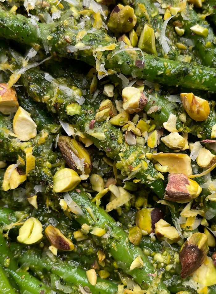 A close-up of fresh mint leaves and whole shelled pistachios.
