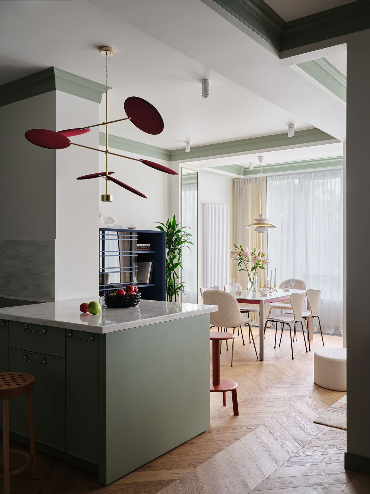 A large sage green kitchen island with a marble countertop in an open-plan dining area.