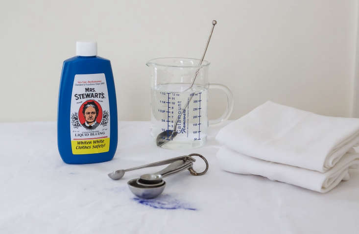 A measuring spoon with a small amount of blue liquid being prepared for a wash.