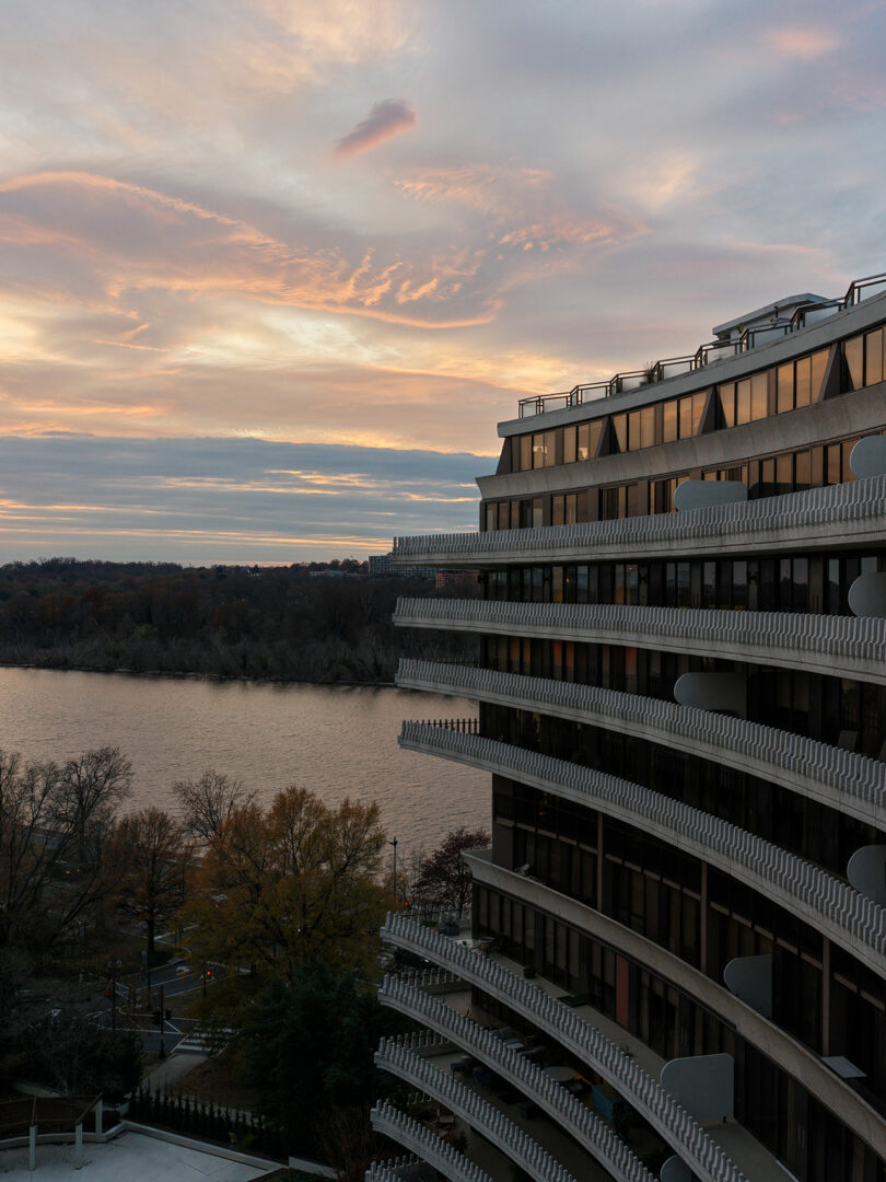 The curved, tiered exterior of the Watergate complex overlooking the Potomac River at sunset.