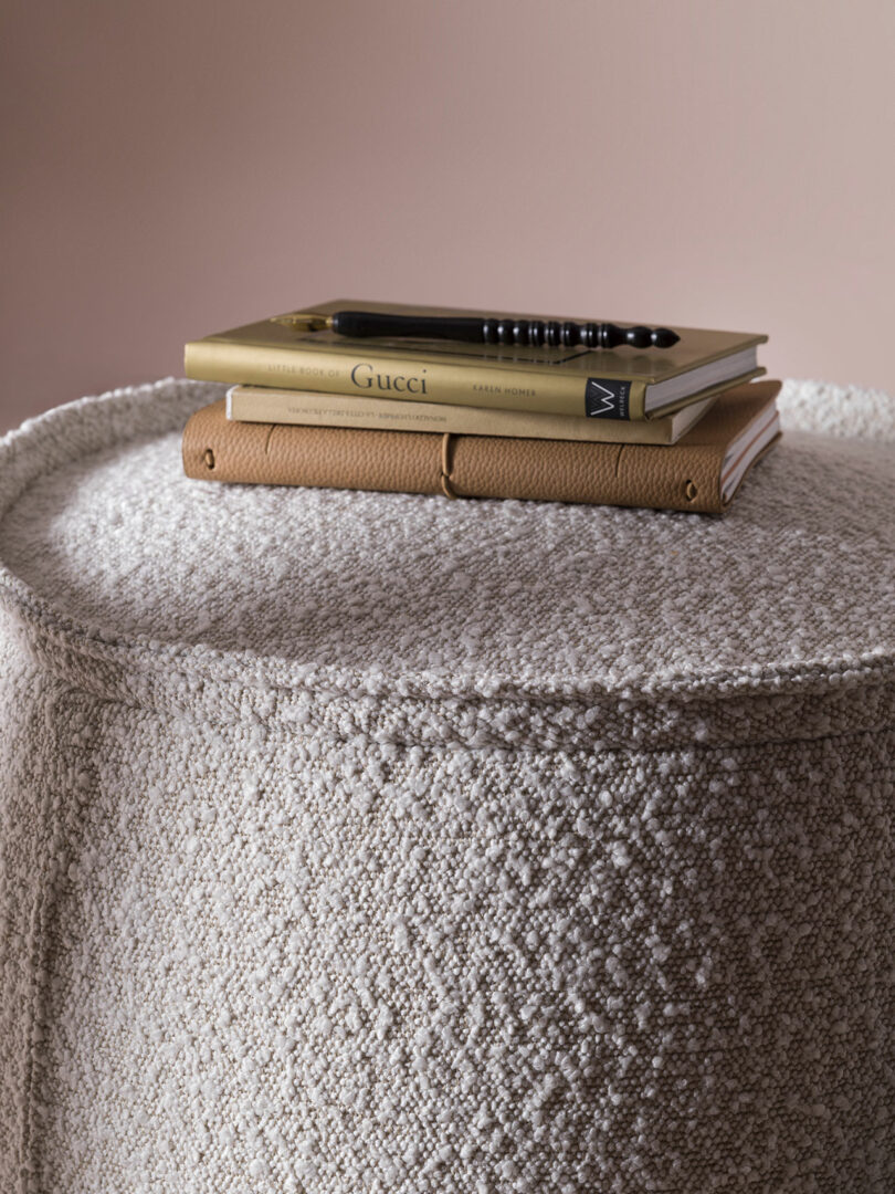 Close-up of a tan leather notebook resting on a textured beige upholstered furniture surface.