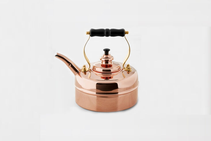 A traditional polished copper whistling teakettle with a classic curved handle.