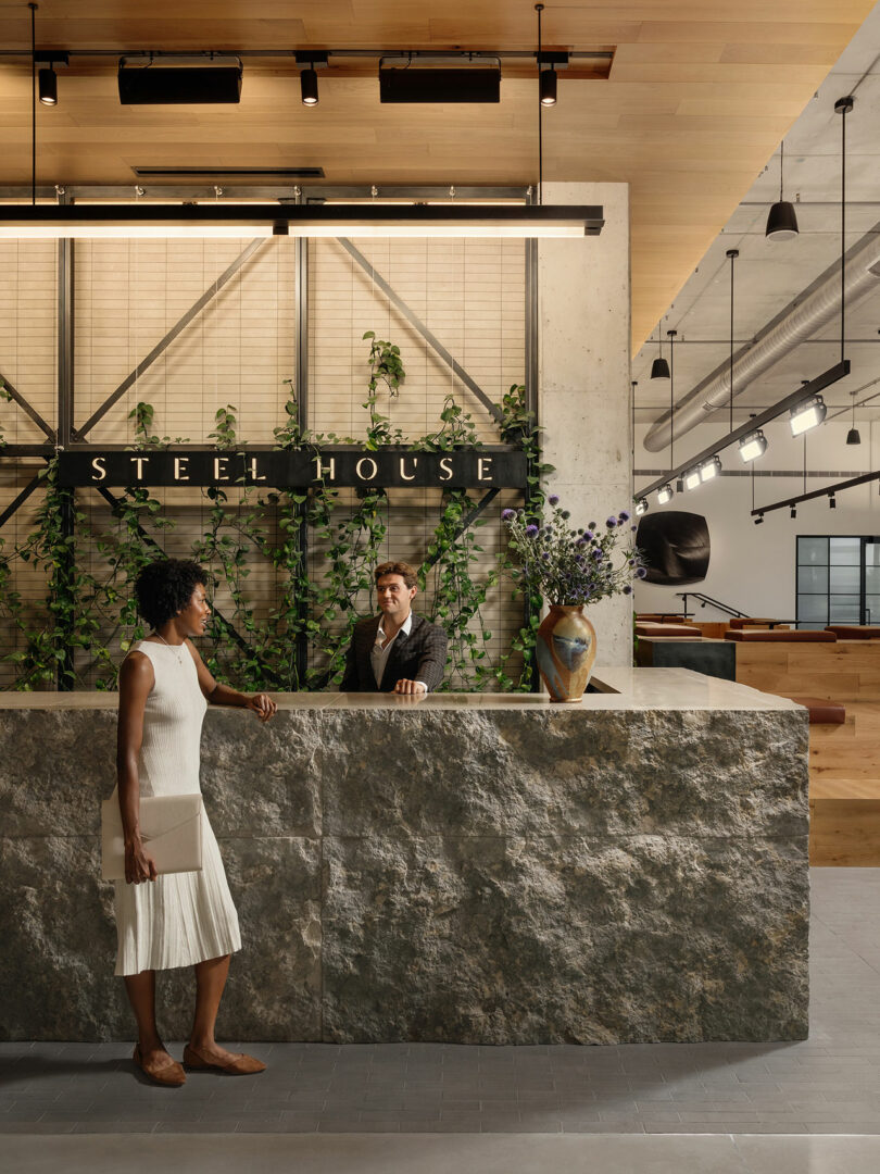 The reception area of Steel House featuring a cleft-stone desk and wooden wall accents.