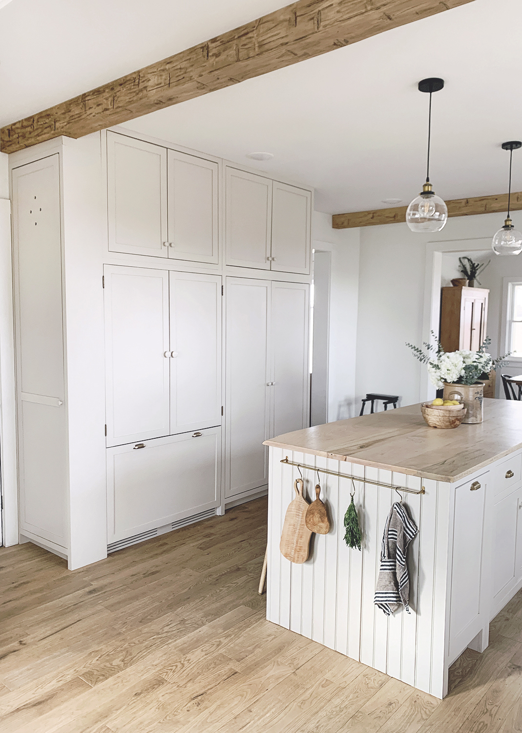A refrigerator integrated with matching cabinet panels and unlacquered brass pulls.