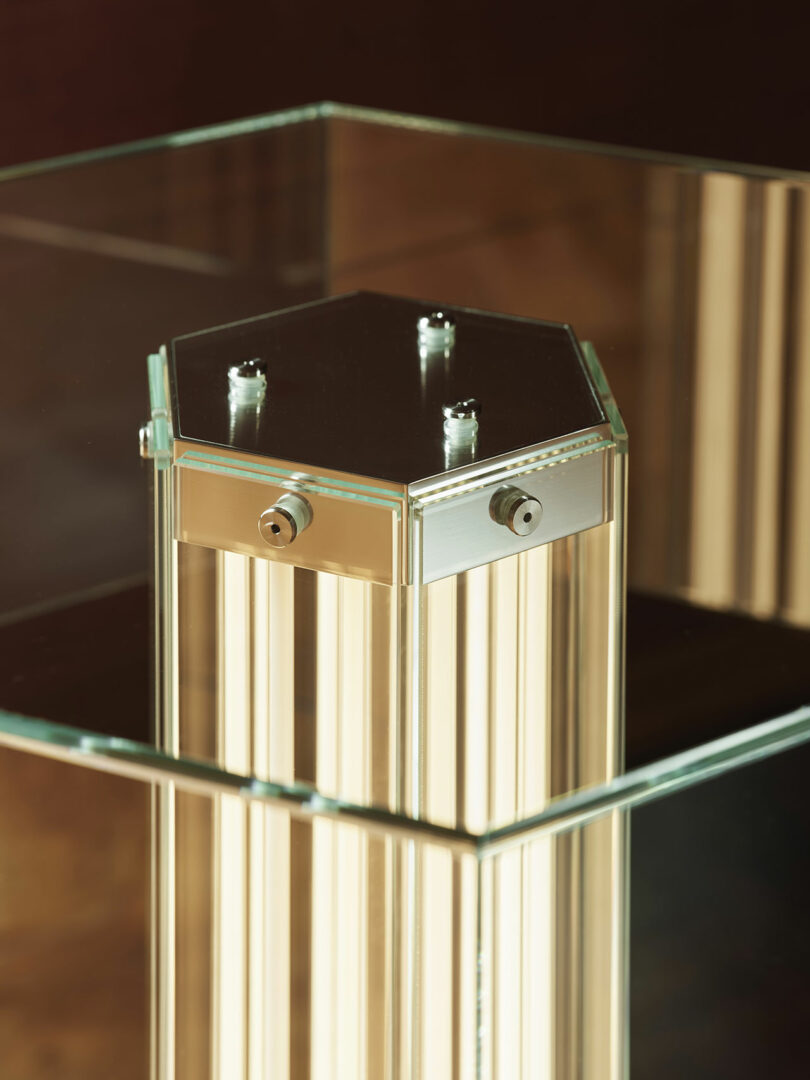 A close-up view of a hexagonal metallic structure with bolts encased in glass panels.