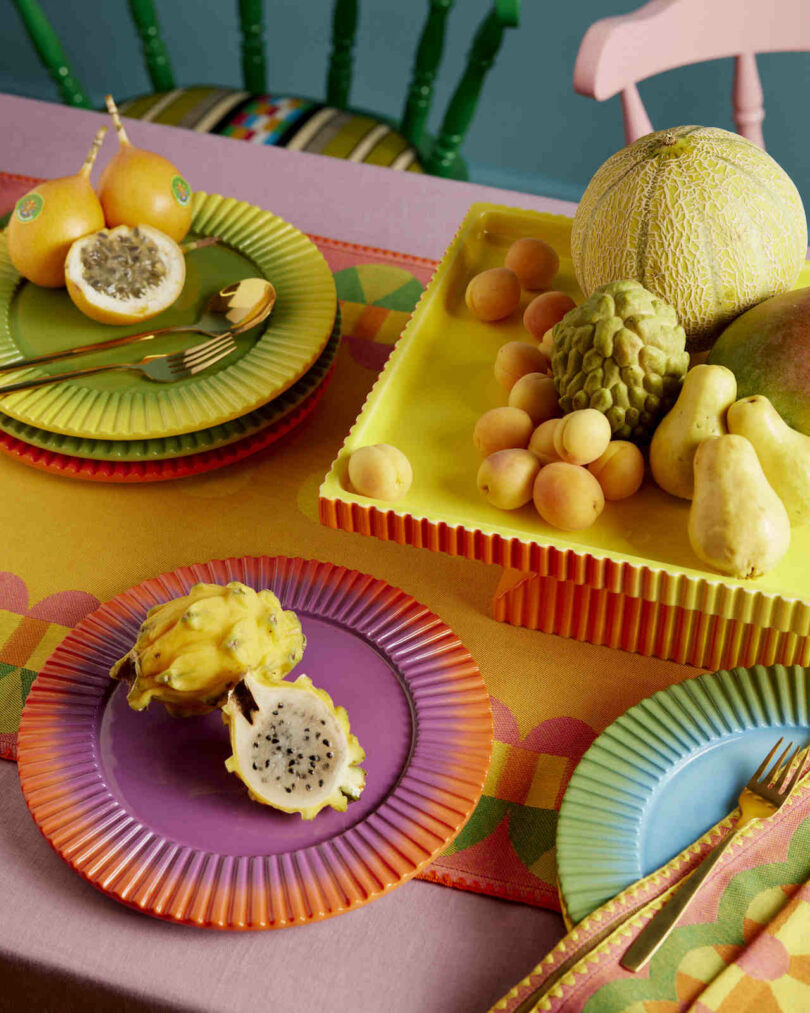 A festive table setting featuring colorful Epin Rere plates, dragon fruit, and passion fruit.