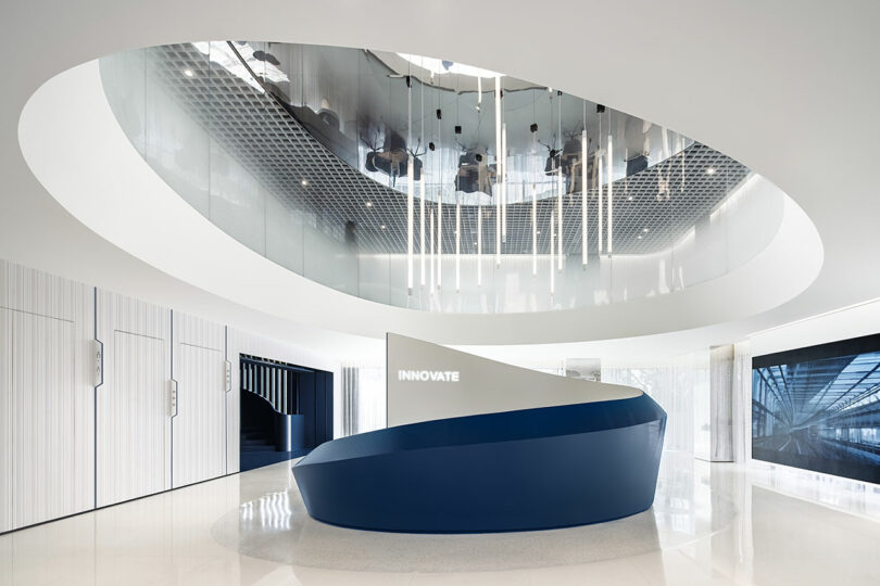 A modern white lobby with a blue curved reception desk and the word 'INNOVATE' glowing on the wall.