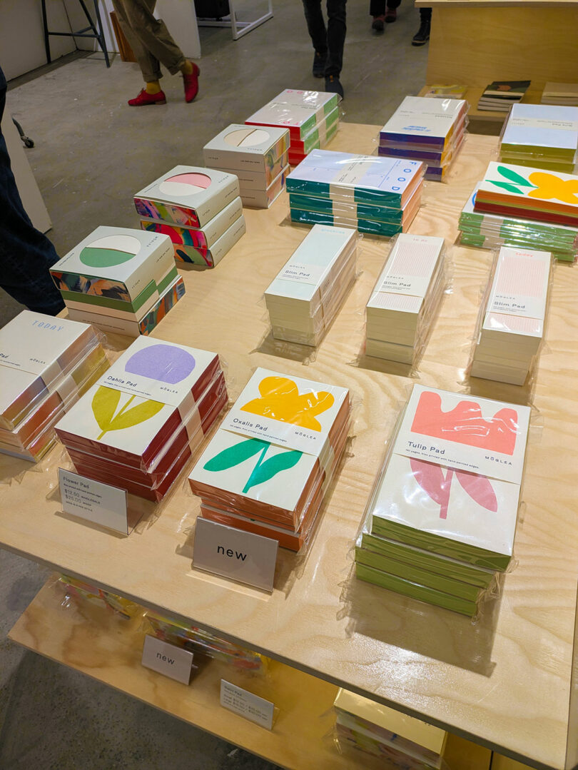 Stacks of colorful, artistically painted notepads and stationery on a wooden display.