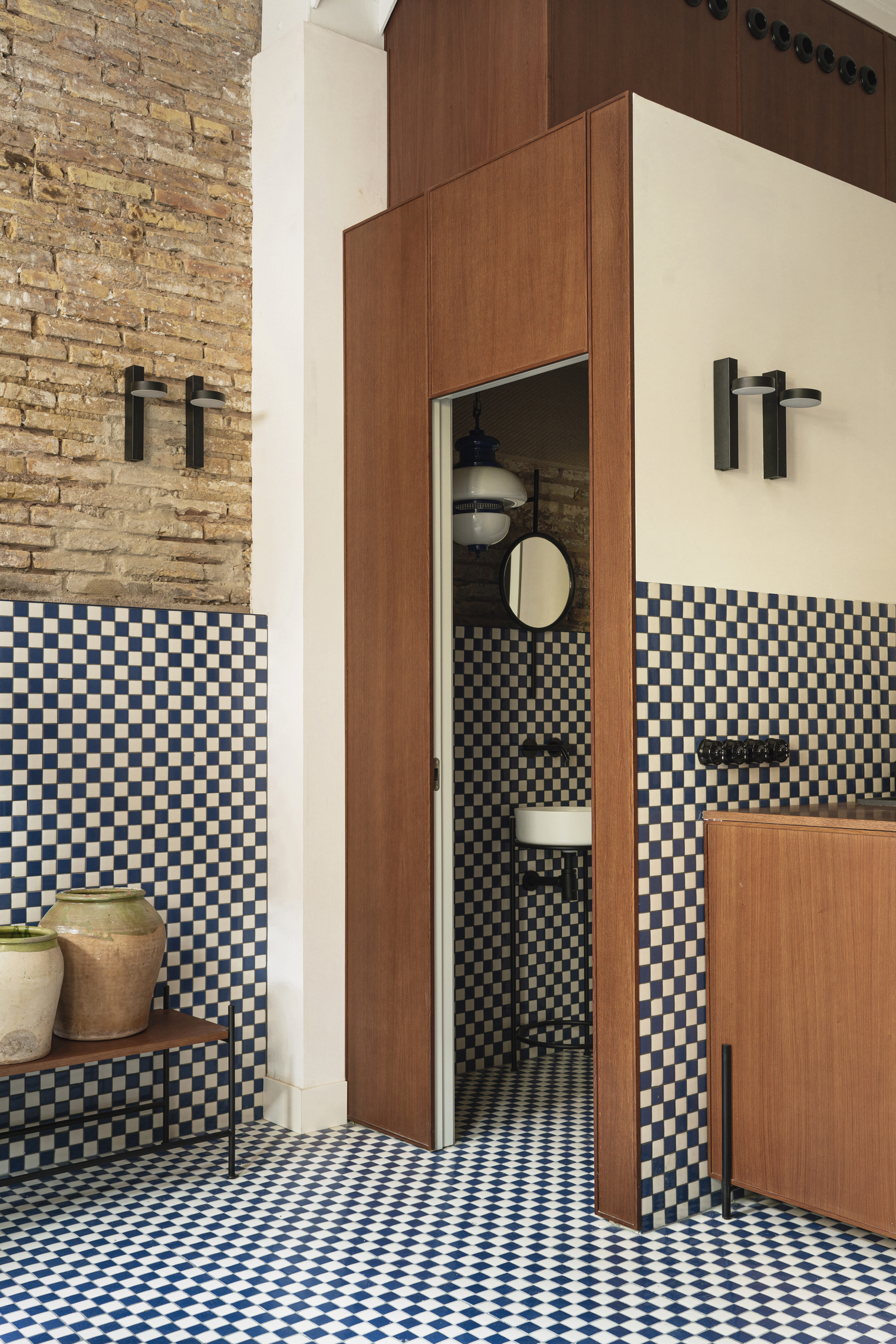 A central wooden oak structure acting as a partition and utility core within a tiled room.