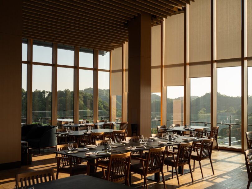 A luxury dining room with wooden furniture and large windows overlooking the natural landscape.