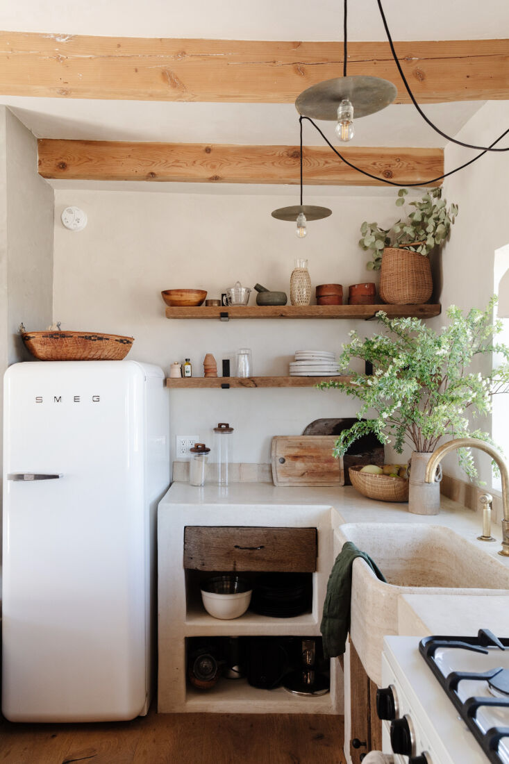 A large rustic stone basin sink with a burnished brass faucet in a modern desert kitchen.