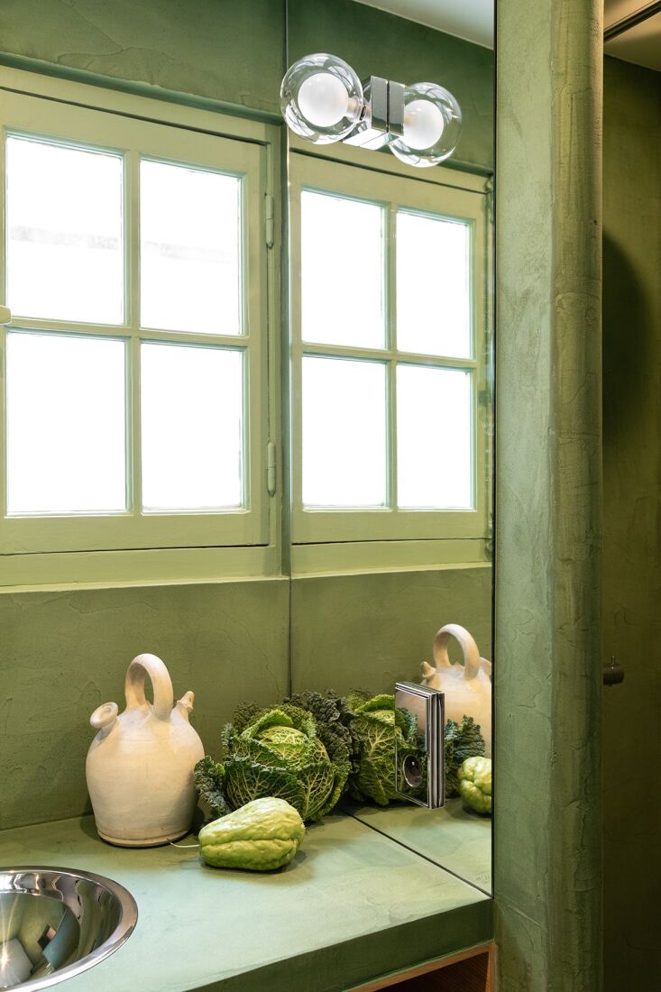 A small bathroom finished entirely in green-colored concrete with a minimalist ceramic sink.