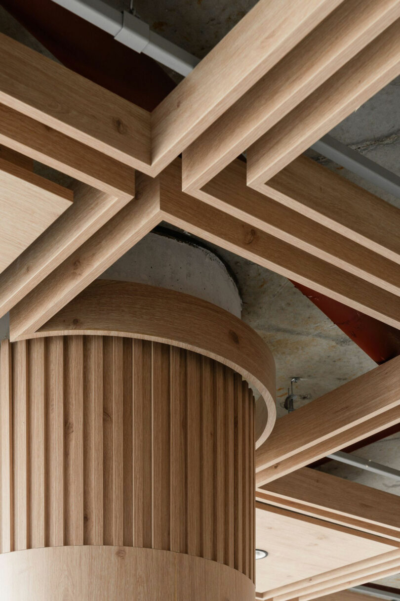 Detailed view of a fluted column and a geometric wooden ceiling design in an industrial-style office.