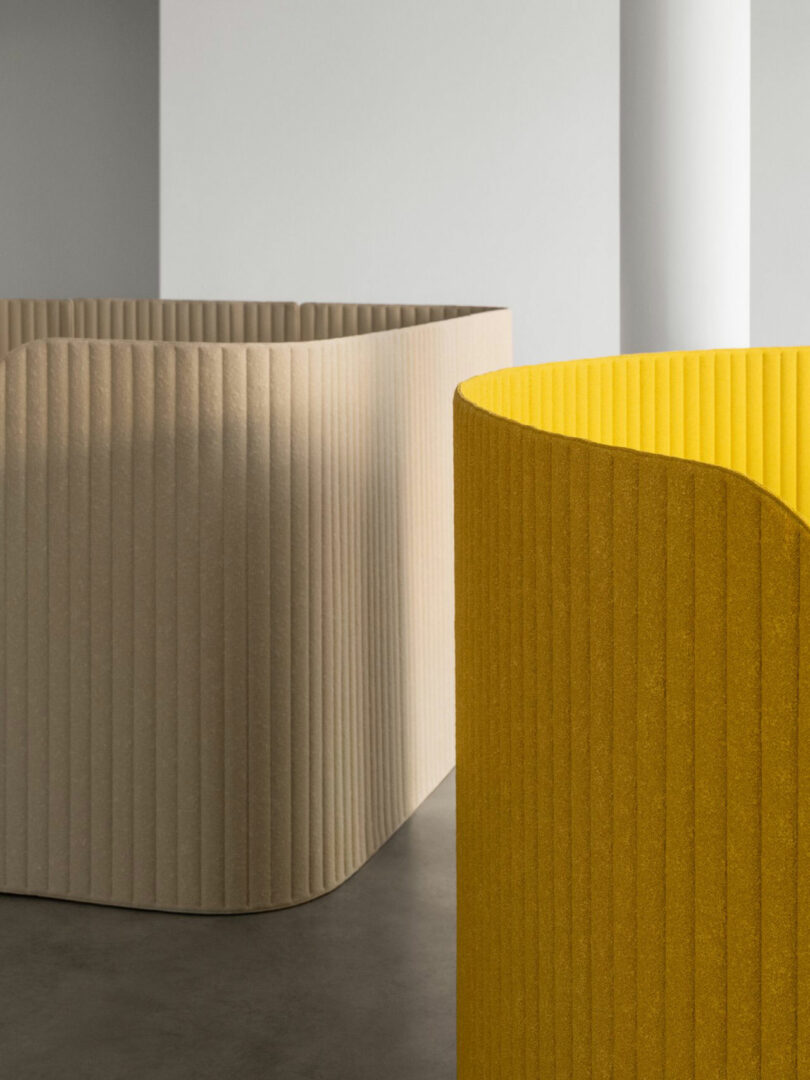 Modular beige and yellow ribbed partitions forming a semi-private meeting zone in a minimalist office.