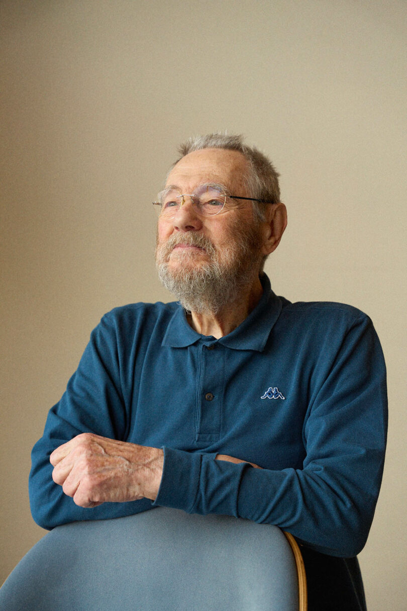 Portrait of designer Tobia Scarpa sitting behind a modern gray chair.