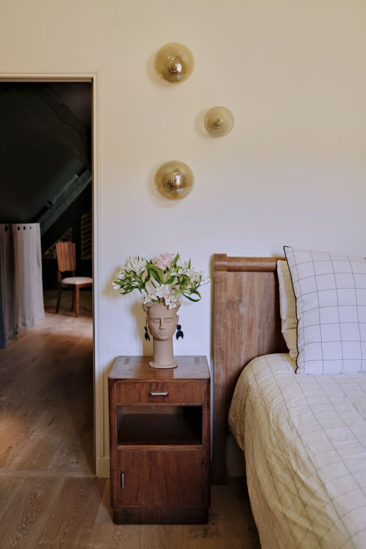 A cozy bedroom at Le Moulin with soft hues and vintage Pierre Frey curtains.