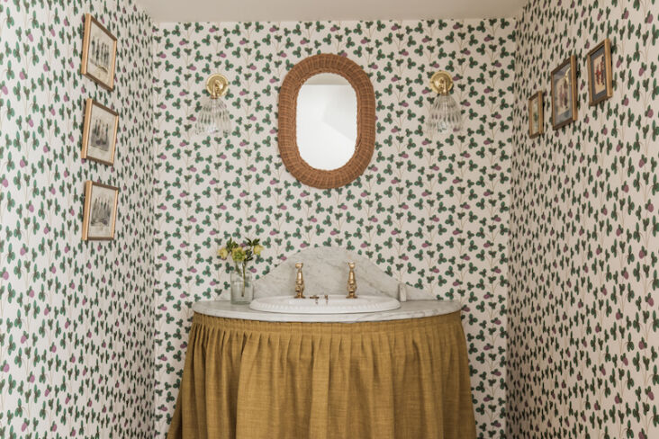 An ochre linen curtain wrapped around a vintage marble sink in a rustic setting.
