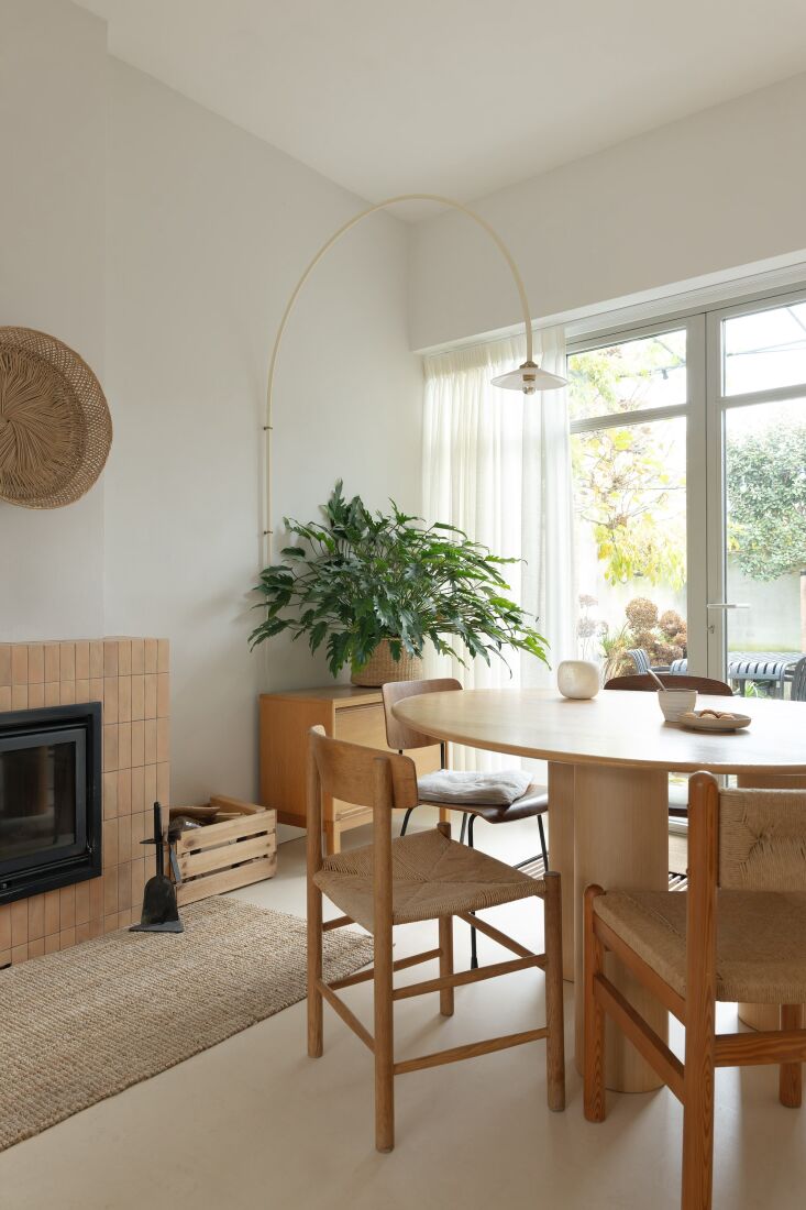 An oval dining table surrounded by vintage chairs under a modern minimalist arc lamp.