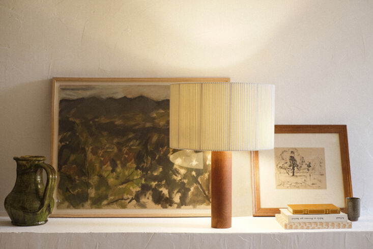 A stack of books by Provençal authors like Albert Camus and Jean Giono on a bedside table.