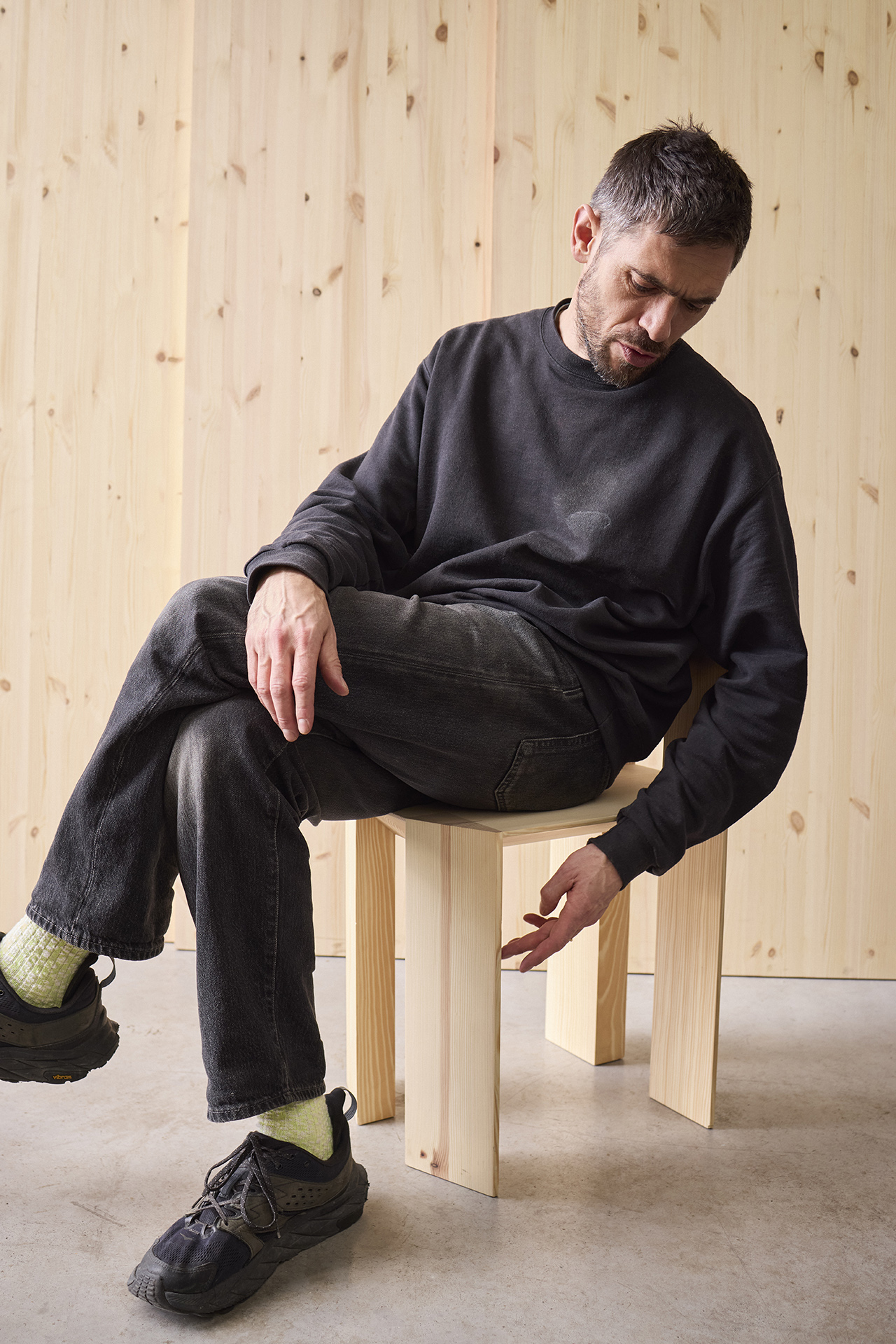 A person sitting on a Max Lamb Min Chair to show its scale and functional use.