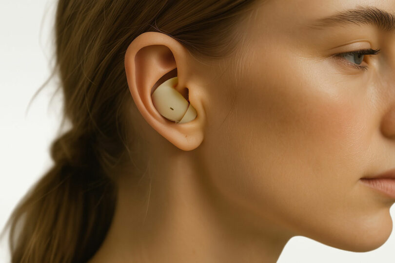 Close-up of a beige SleePod earbud nestled perfectly within a woman's ear concha.